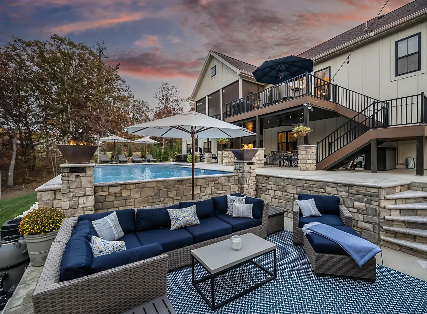Outdoor living space with stone retaining walls, seating area, and elevated pool at a Midwest residential home in Glen Carbon IL during sunset.