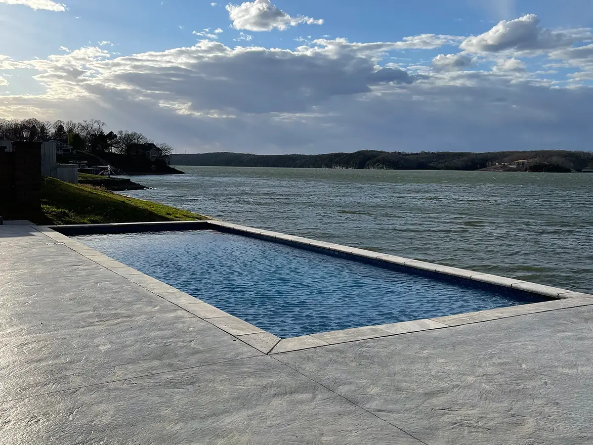 Modern rectangular concrete swimming pool overlooking a river with expansive concrete pool deck at a Glen Carbon IL residential property.
