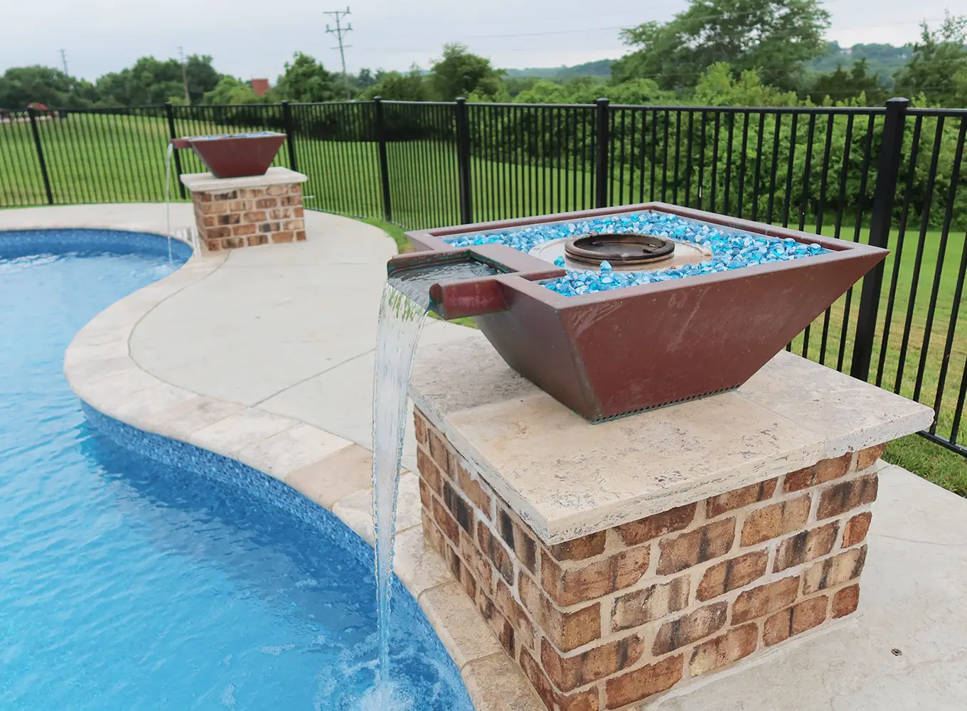 Custom fire bowl water feature spilling into a residential swimming pool in an O'Fallon IL backyard.